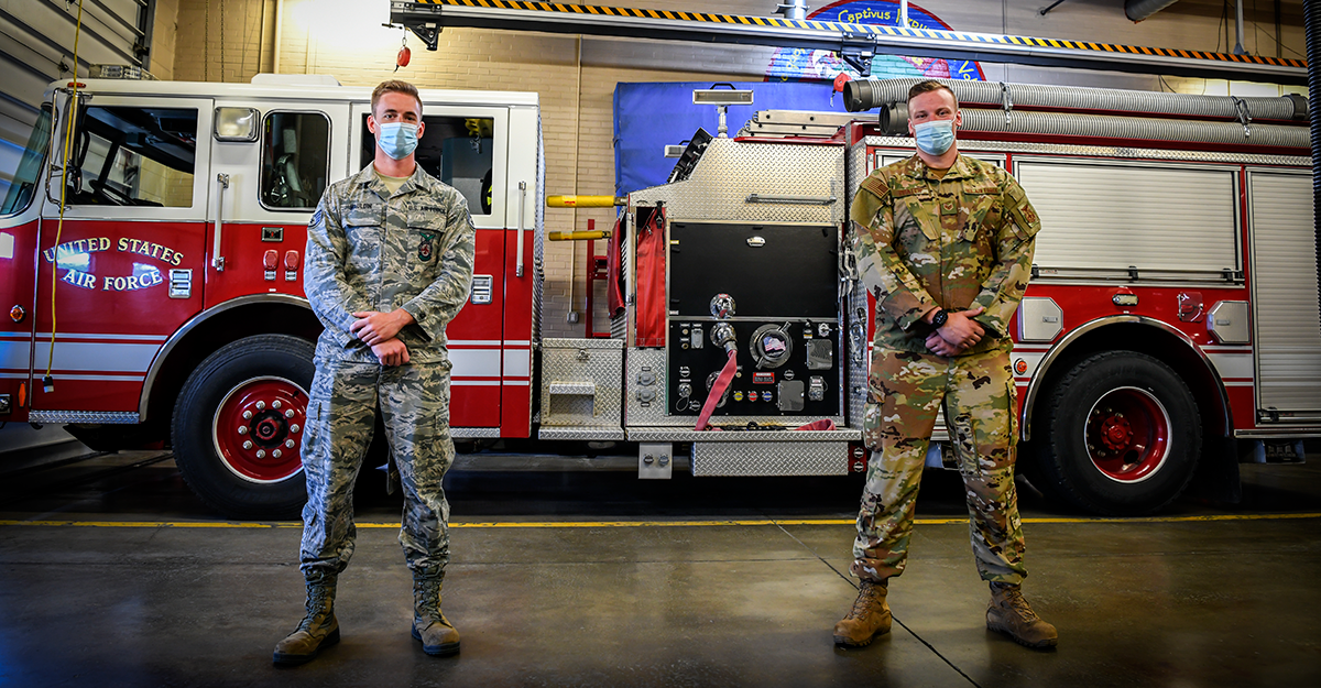 Staff Sgt. Joshua Prater and Staff Sgt. Michael Mauldin stand in front of firetruck.