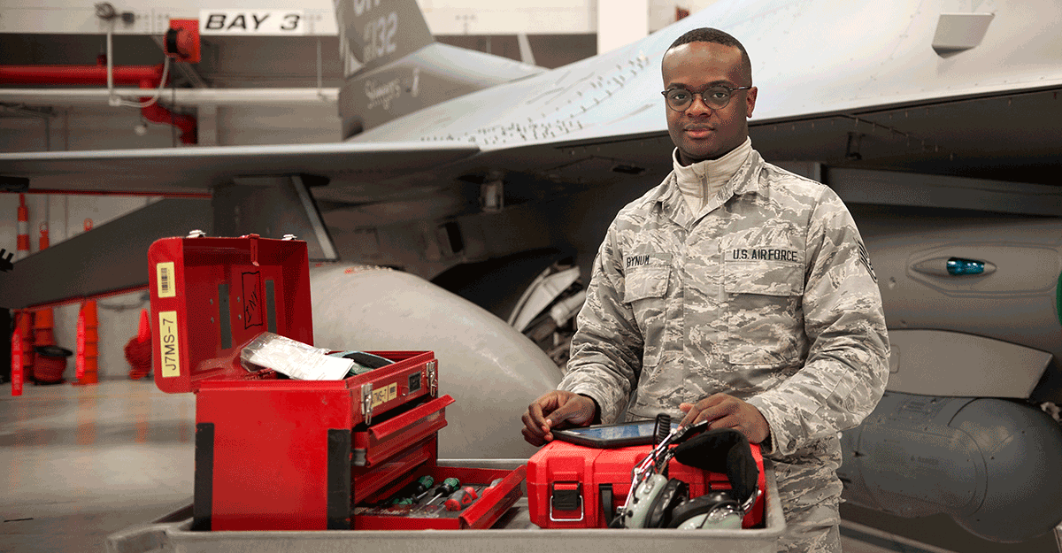 Bynum stands in front of F16 with toolbox.