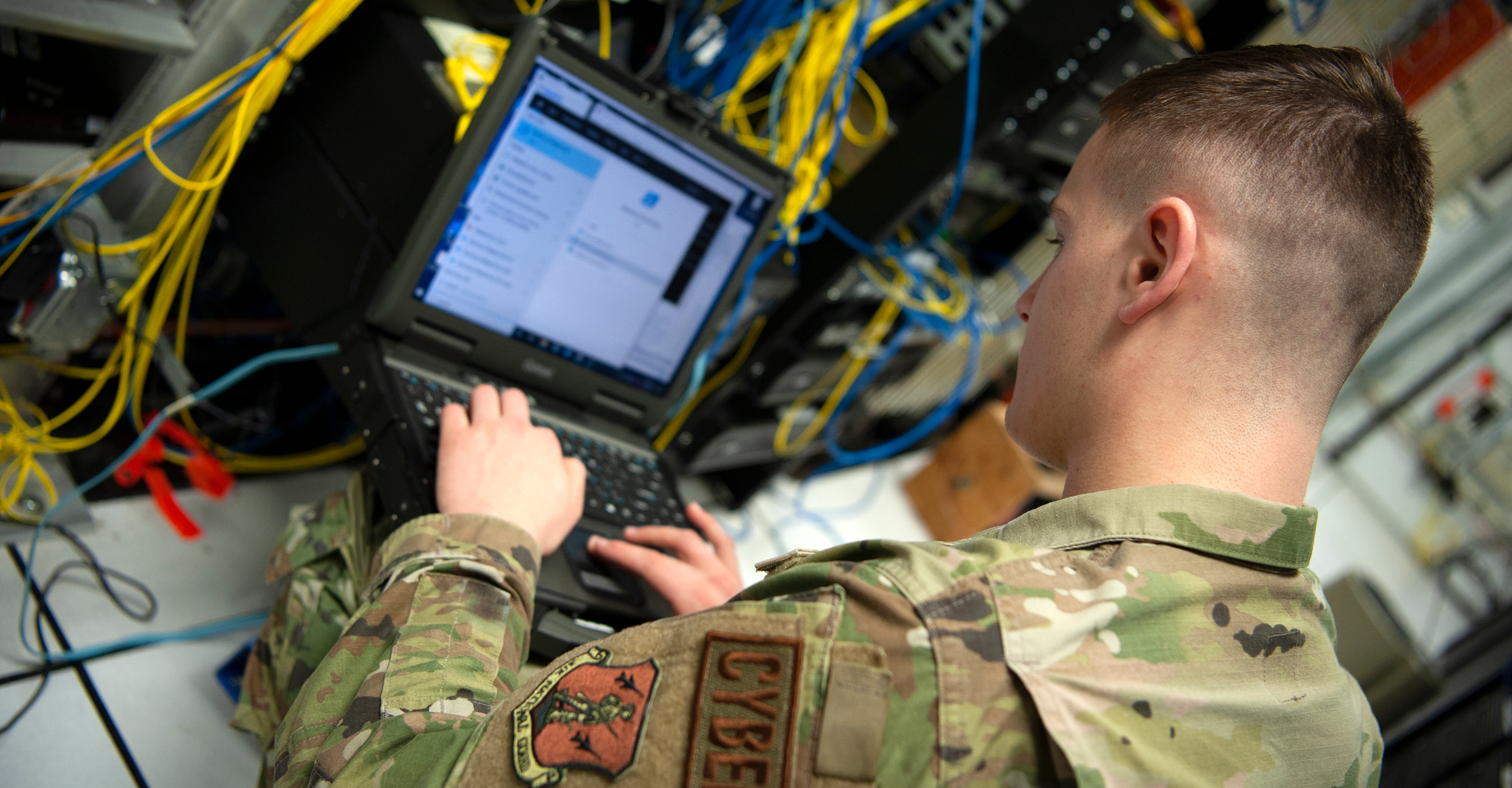 A cyber specialist on laptop with cables all around.