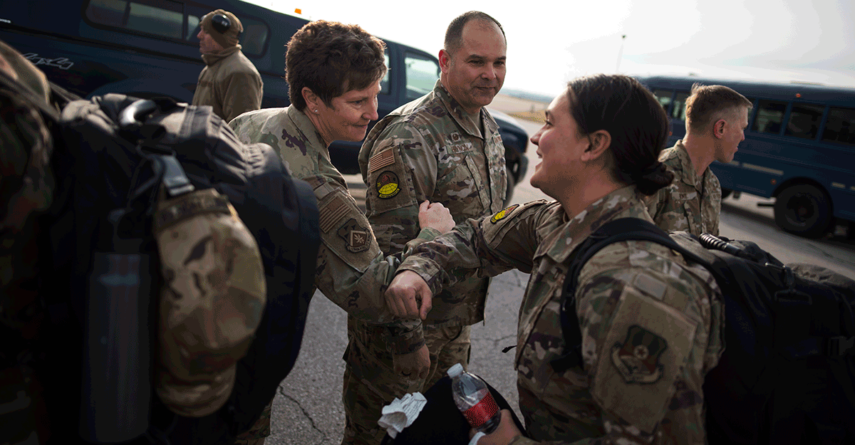Command Chief Master Sgt. Heidi Bunker touches elbows with an Airman — as an alternative to a traditional handshake - as airmen leave for a deployment. 