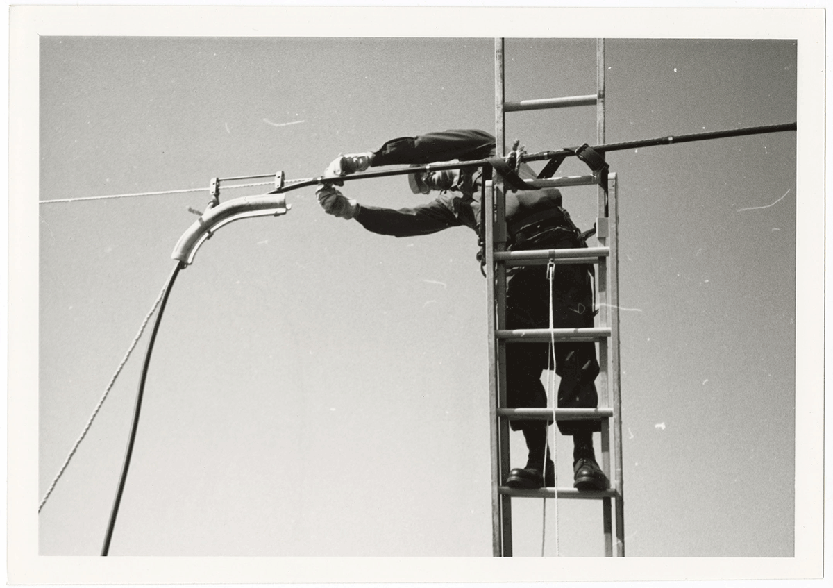 Tech. Sgt. straps cable while securely attached to his ladder.
