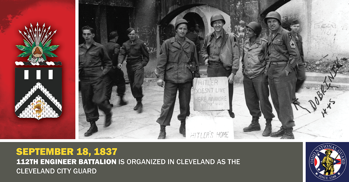 Soldiers pose for a picture in front of a sign that reads 'Hitler doesn’t live here anymore. Why not?'