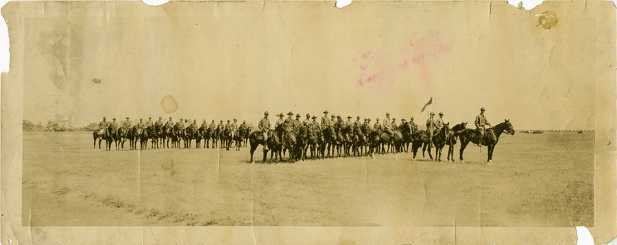 Sepia tone panoramic of calvary on horses in formation in a field