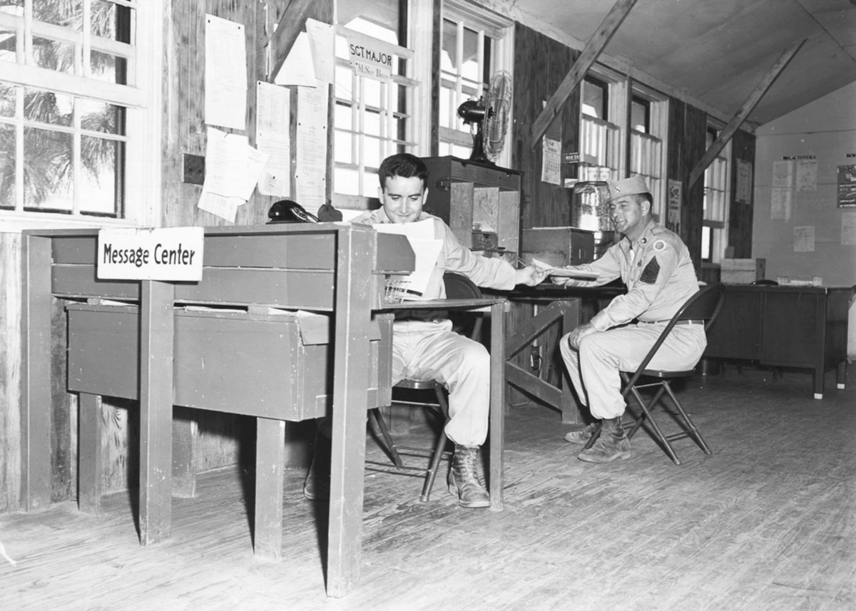 Black and white photo of Soldiers at desks in message center.