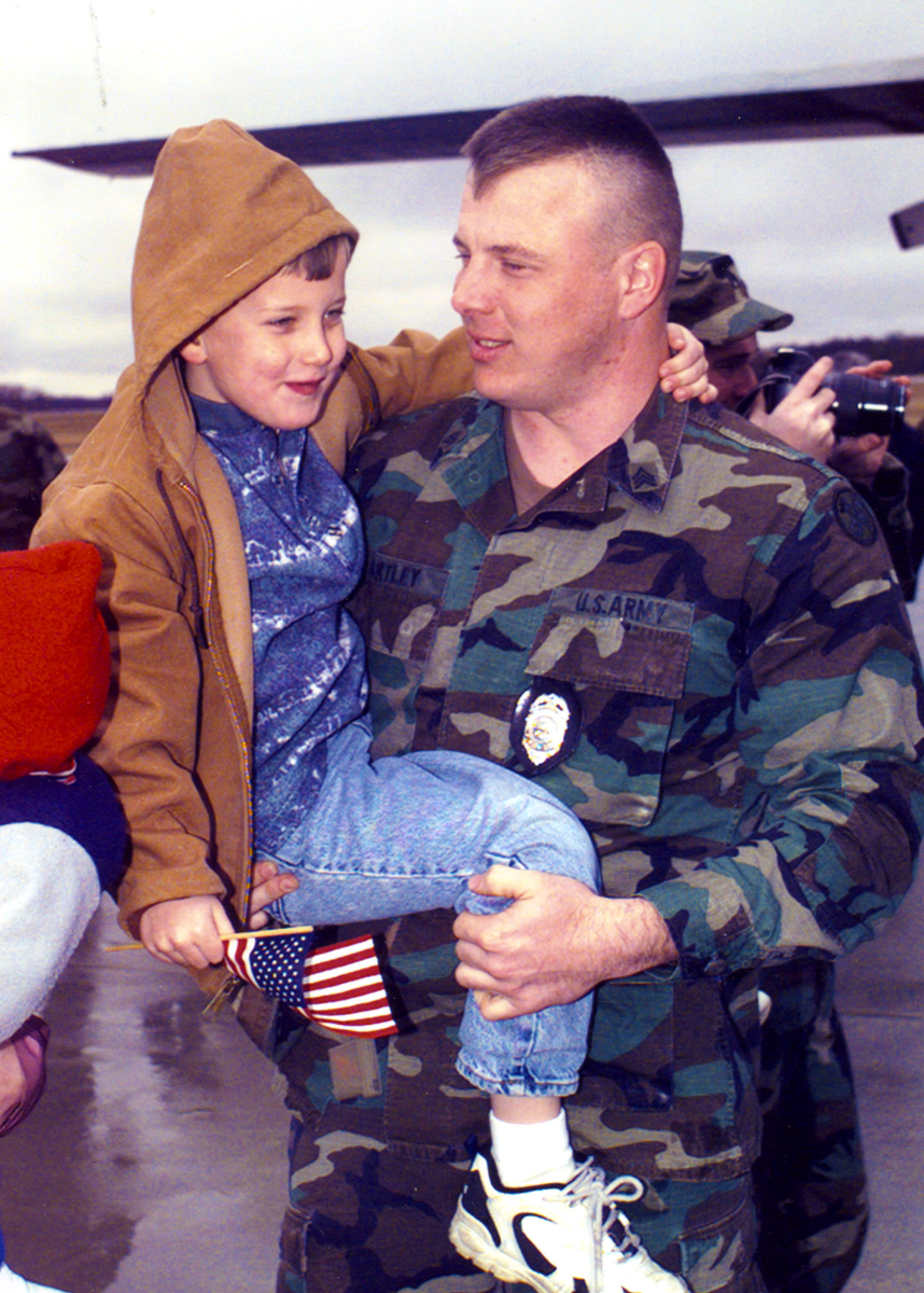 Color photo of Soldier holding young son.