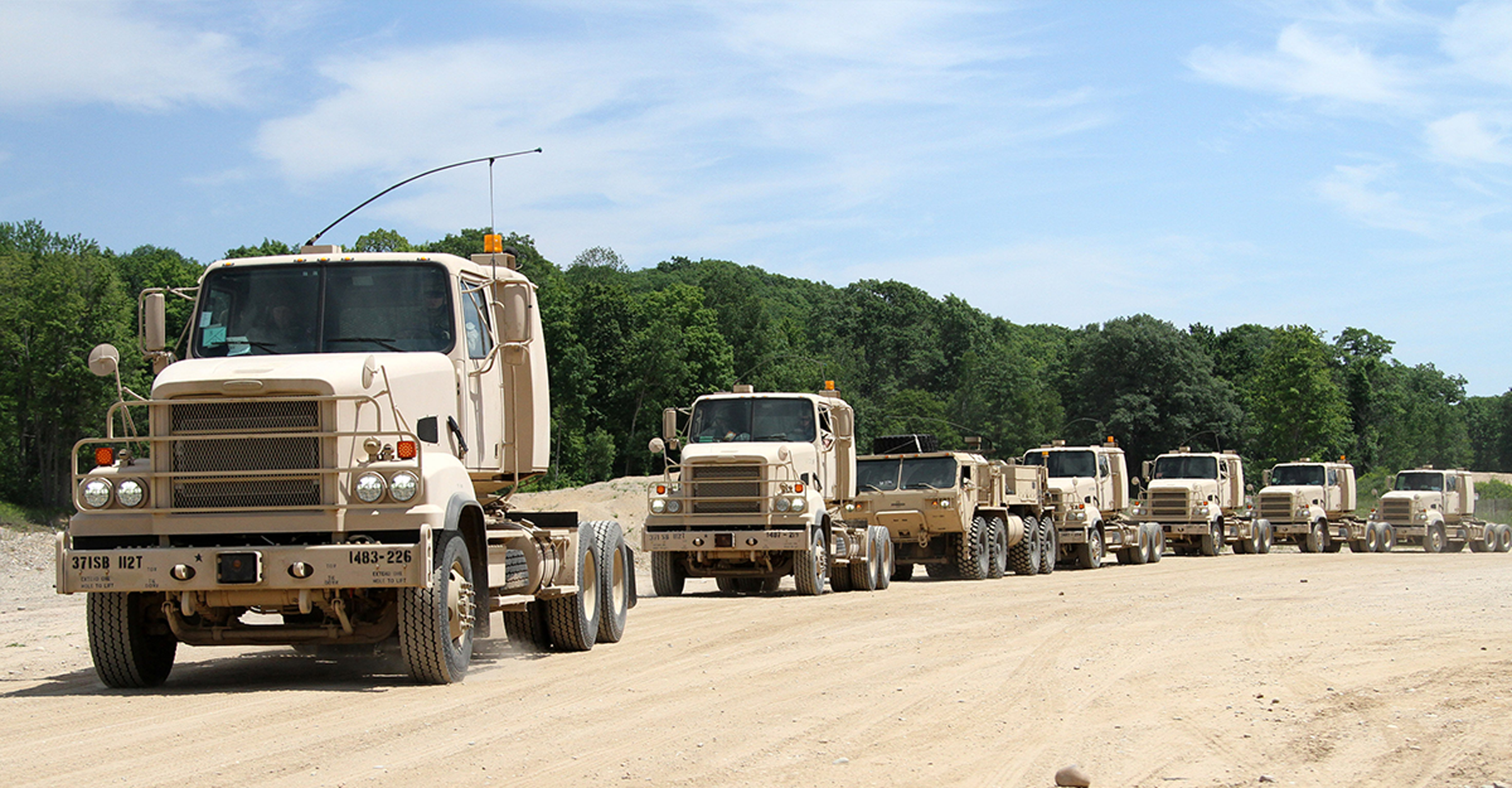 Army vehicles in a line on a dirt road