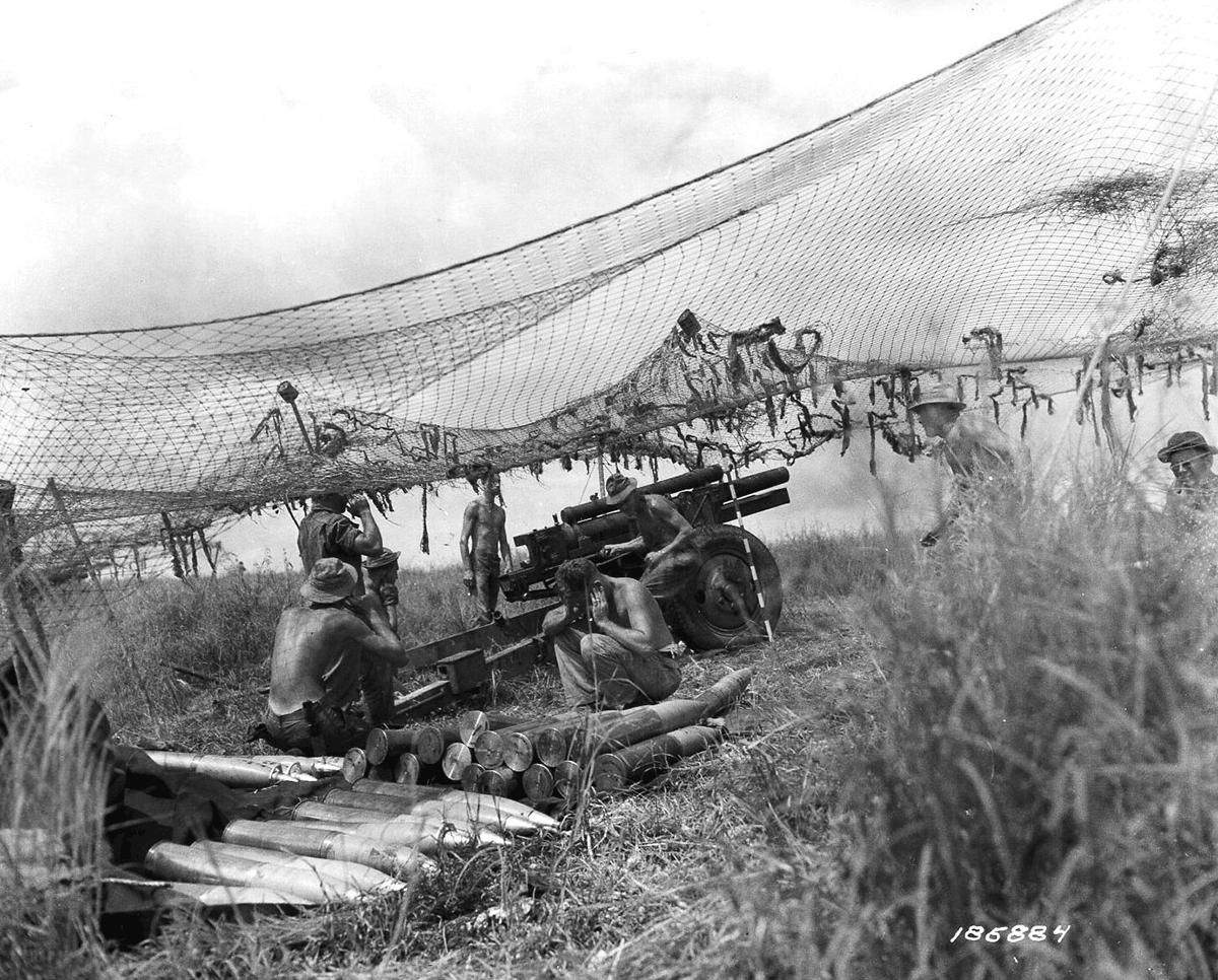 Black and white photo of Soliders under net covering in field.