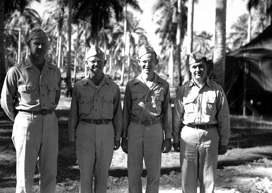Black and white photo of 4 soldiers standing for photo.