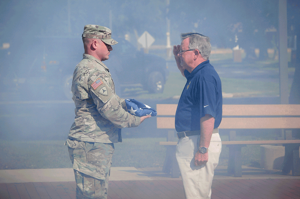 Soldier present folded flag to man saluting.