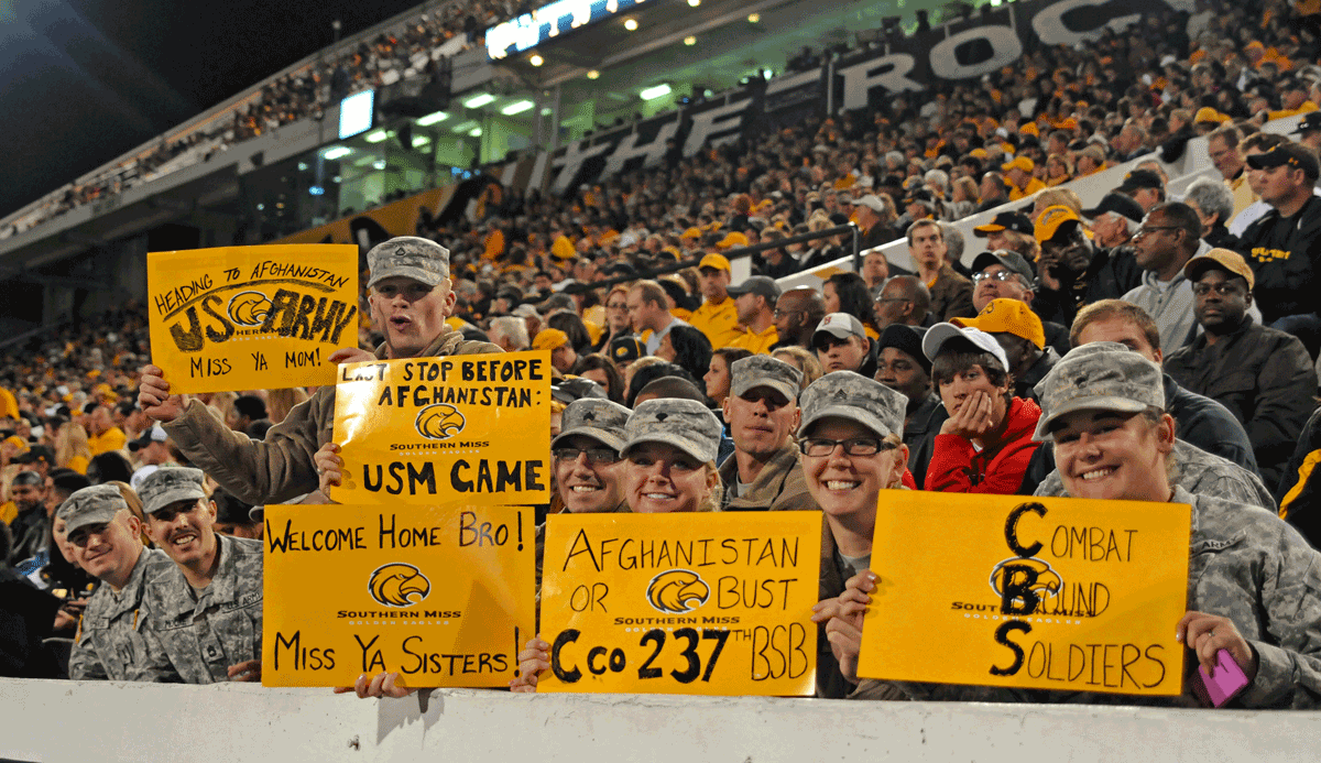 Soldiers holding signs in football stadium.