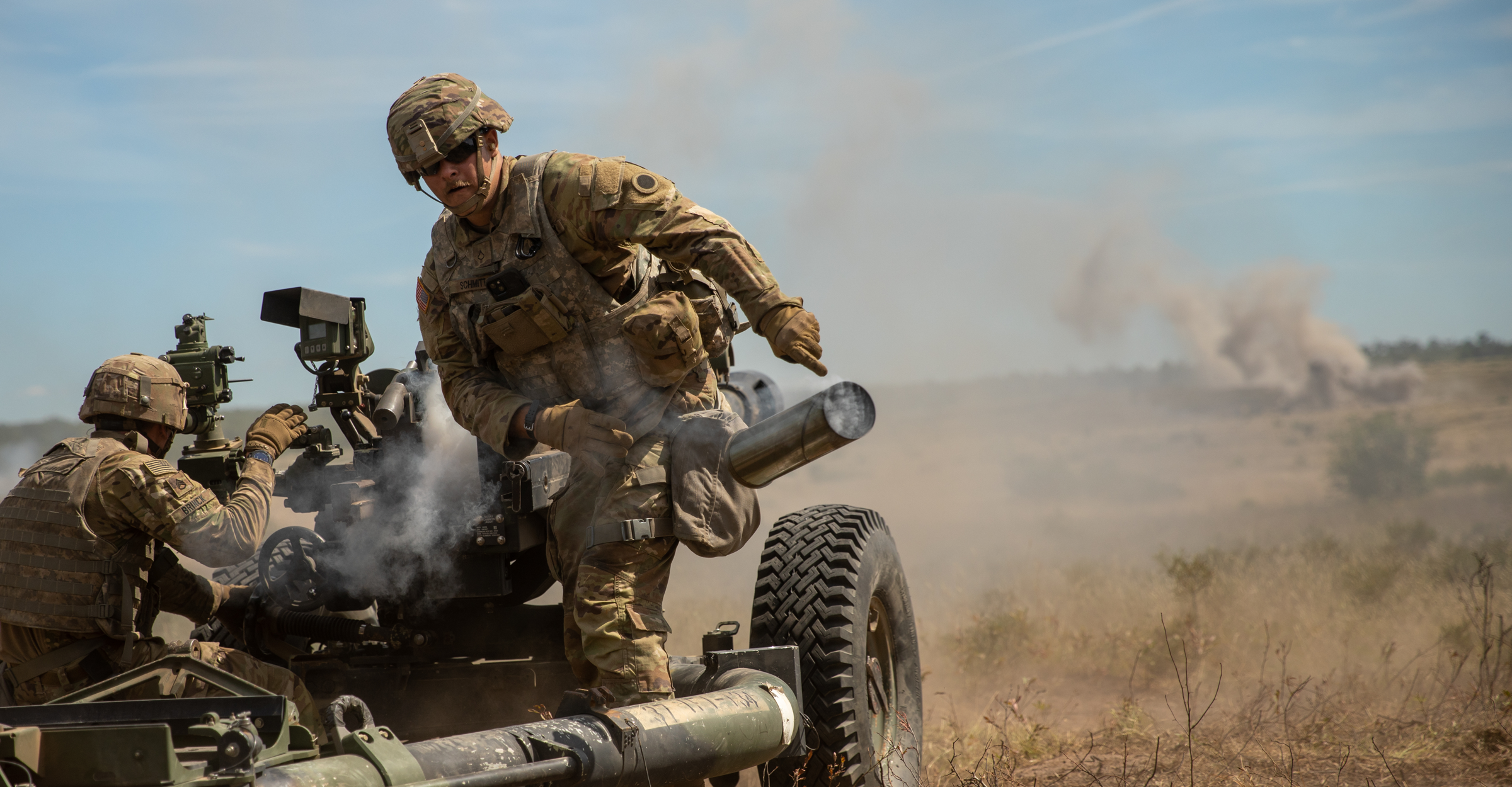 Soldier tosses the casing of a 105 mm artillery round