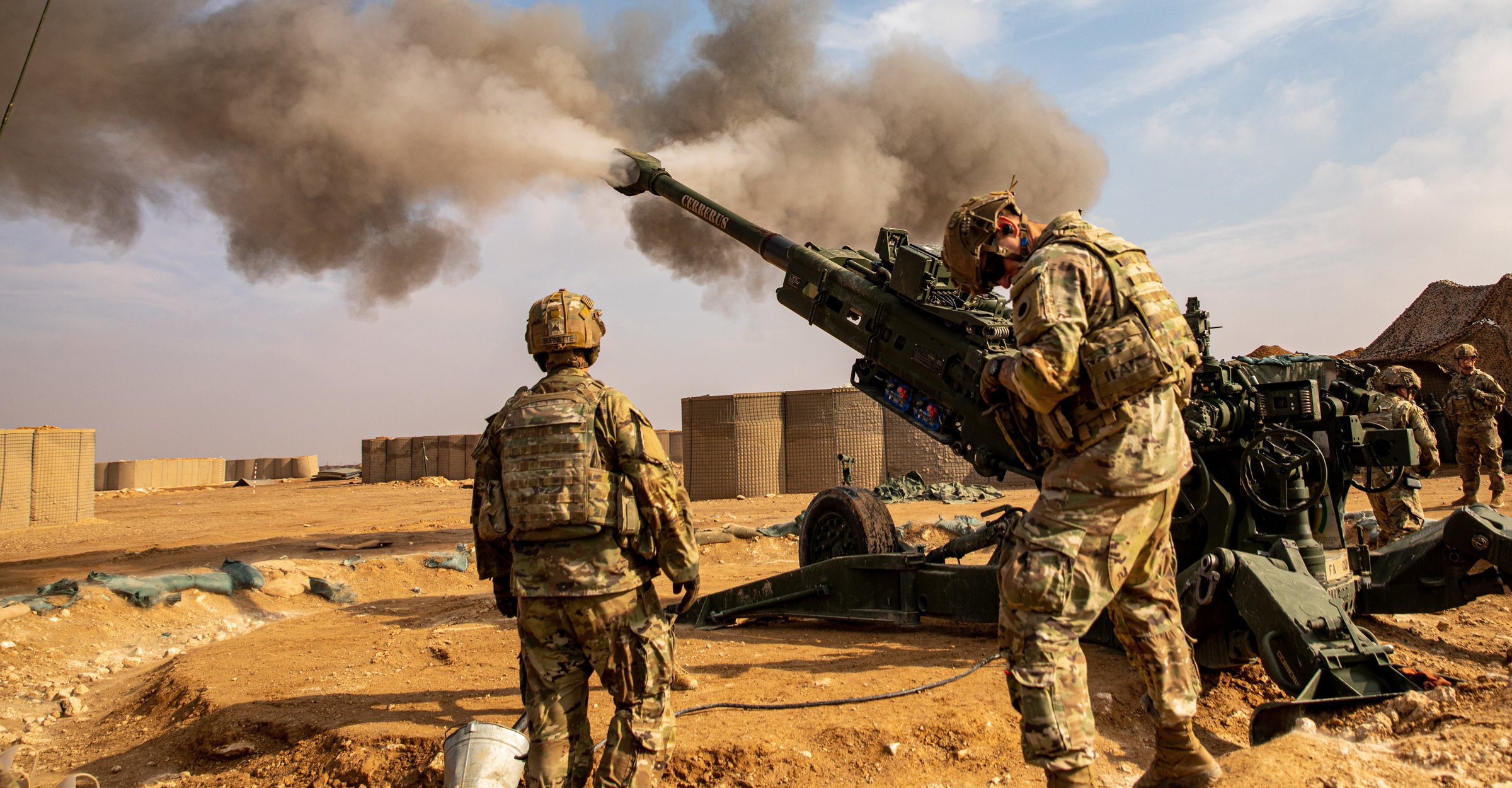 Soldiers using artillery weapons in desert land.