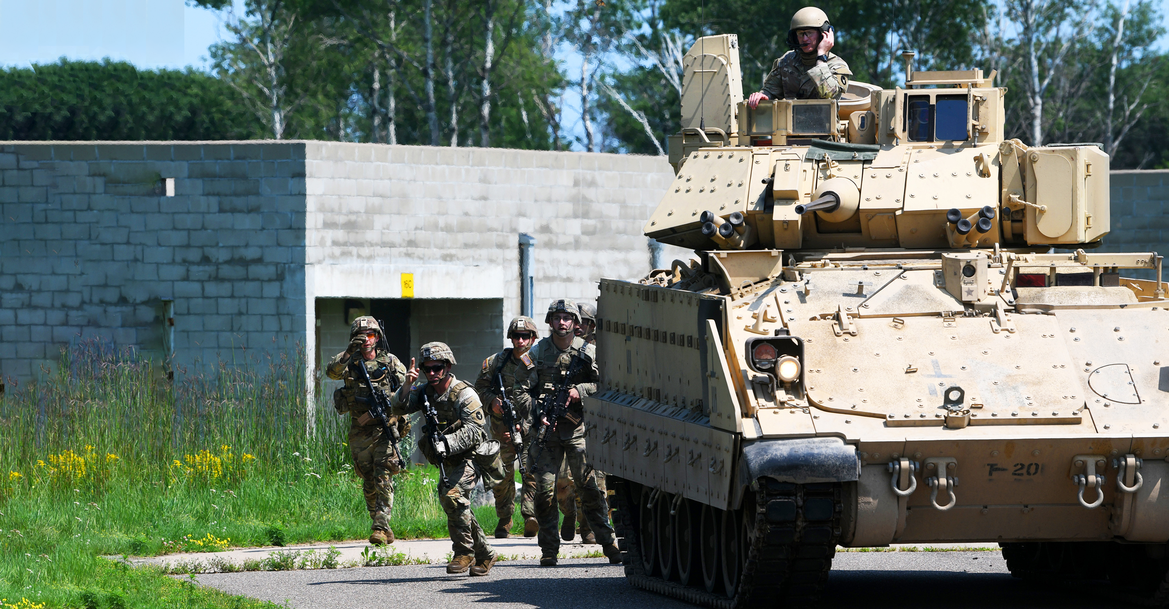 Soldiers run alongside an M2A3 Bradley Fighting Vehicl