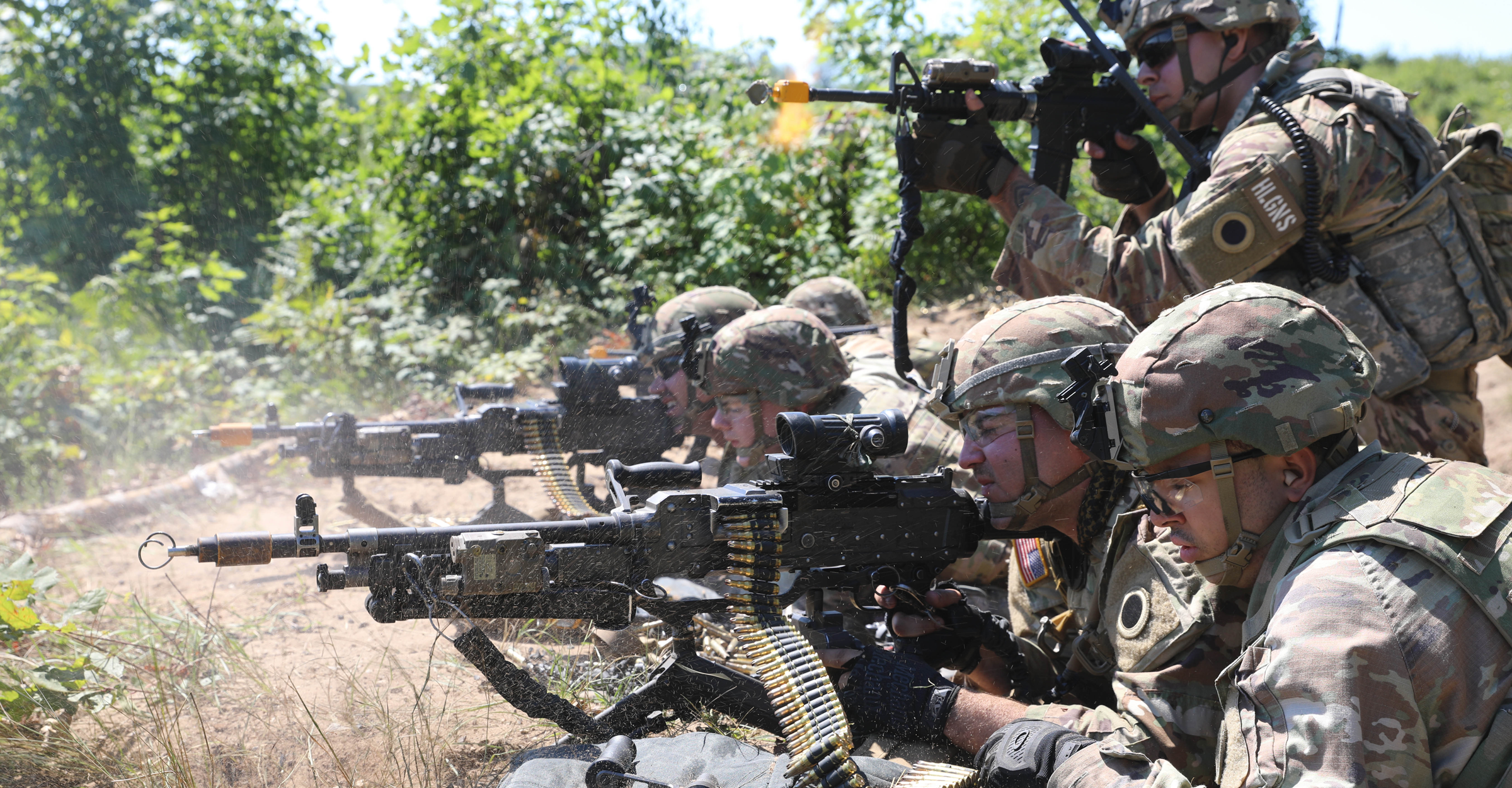 Soldiers providing cover-by-fire on ground in field