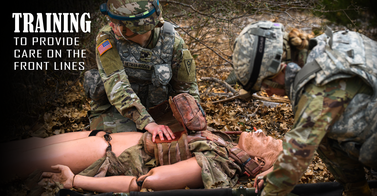 Soldiers treat simulated casualty dummy on ground. 