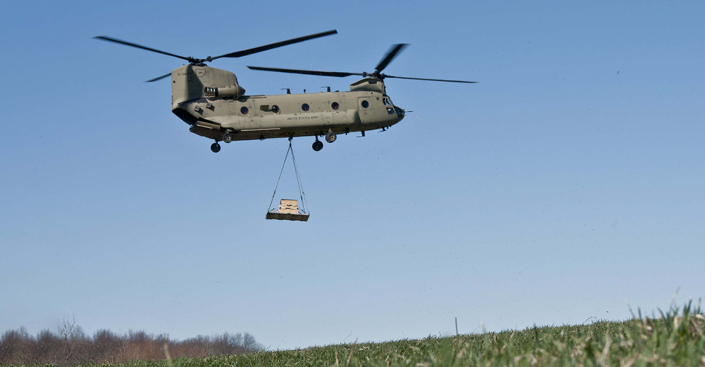 COMPANY B, 3RD BATTALION, 238TH AVIATION REGIMENT: A CH-47 Chinook conducts a sling load of a heavy drop pallet in a muddy drop zone. CH-47 crews operate a versatile, tandem-rotor heavy-lift used for troop transport, artillery placement and battlefield resupply.