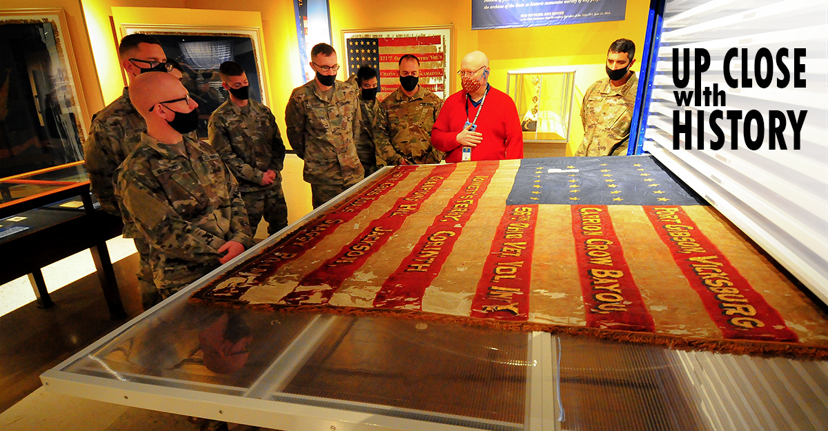 Soldiers standing around historic flag collection.
