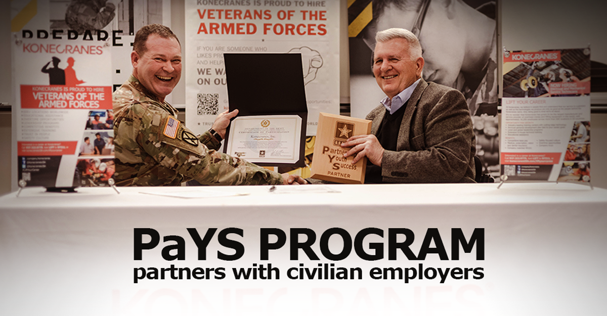 Soldier and man hold plaque at exhibit table.