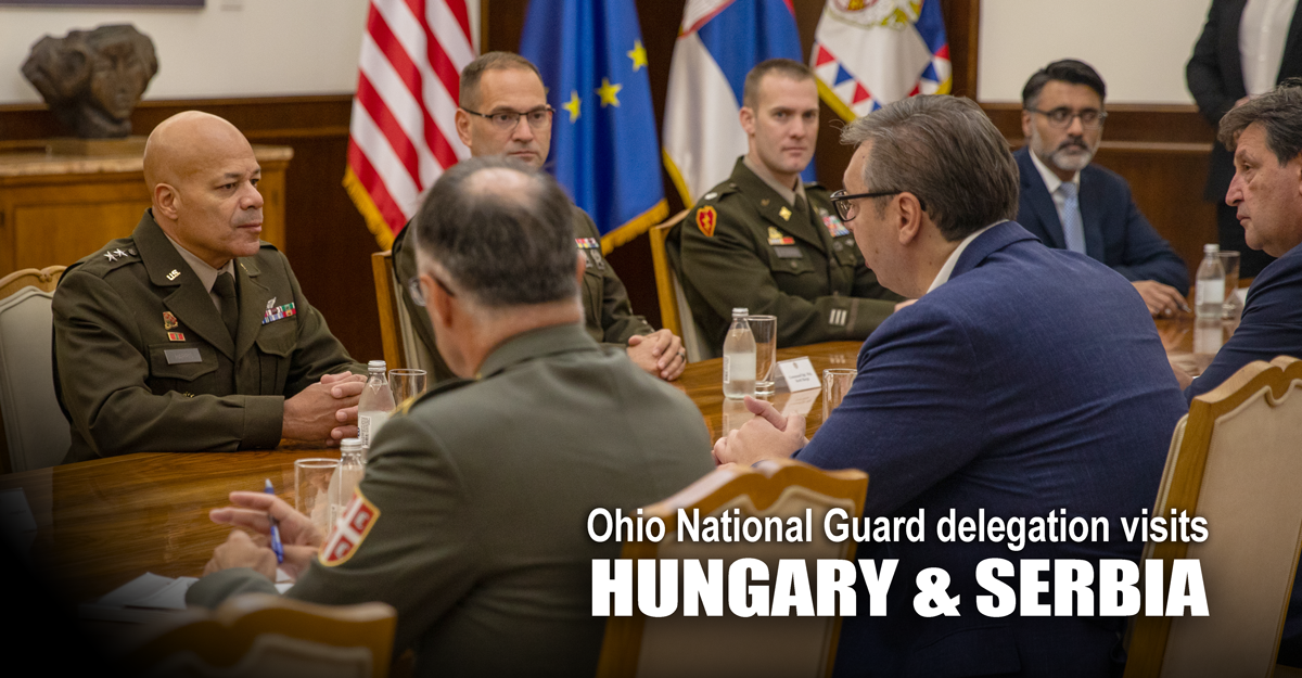 Members of the Ohio National Guard and Hungarian Defense Forces pose with an Ohio flag in from of a JAS-39 Gripen