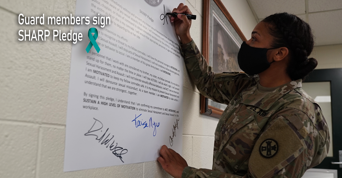 Female Soldie signs pledge on wall.