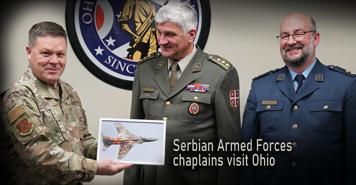 Asst. Adj. gen for Air holds up illustration while Serbian Chaplains stand beside him.