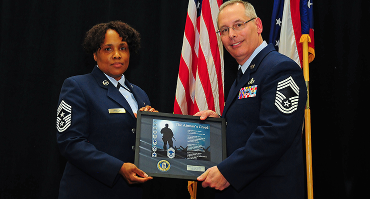 Chief Master Sgt. Phillip D. Smith holds framed print with Chief Master Sgt. Tamara R. Phillips.
