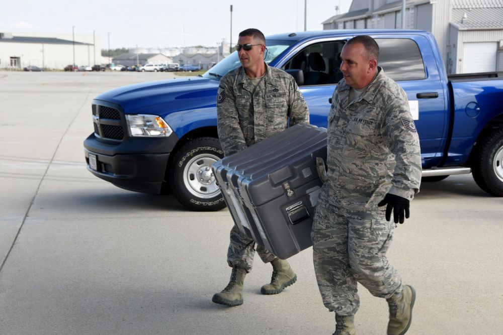 Master Sgt. Jason LaPorte and Tech. Sgt. Kevin Harrison carrying equipment to C-130H Hercules.