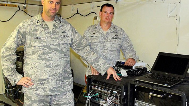 Two airmen from the 269th Combat Communications Squadron pose with communications eqipment.