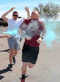 Capt. Jonathon Shaw  (right), operations officer with Company B, 2nd Battalion, 19th Special Forces  Group, covers his face as he gets powder thrown on him and Chief Warrant Officer 3  Kyle Davidson, a pilot with the 1st Battalion, 137th Aviation Regiment, follows through the first color station.