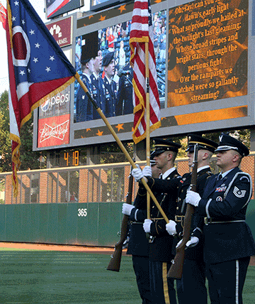 Soldiers and Airmen composing an Ohio National Guard joint color guard display flags during the national anthem.
