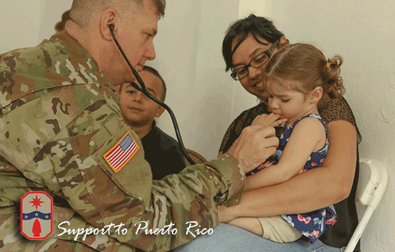 Maj. Donald McHone (left), a registered nurse with the 285th Medical Company (Area Support), uses a stethoscope to listen to the breath and heart sounds of a young patient.