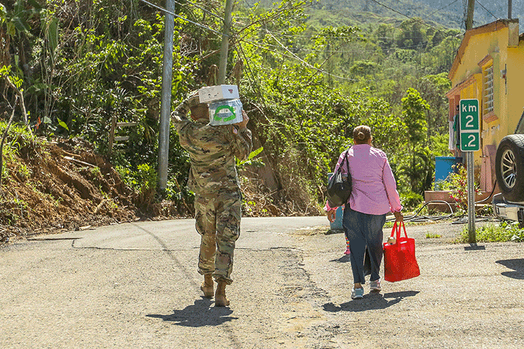 Capt. David Kirker, a behavioral health specialist attached to the 285th Medical Country (Area Support), carries water and a case of food to an elderly Puerto Rican citizen's house.