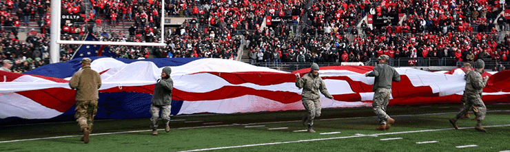 Ohio National Guard members unfurl Amercan flag on the OSU football field.