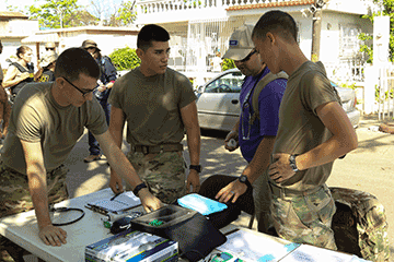 Three Army health care specialists prepare a triage station on a residential street.