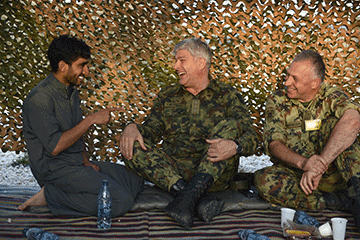 Three Soldiers sitting on floor in tent laughing.
