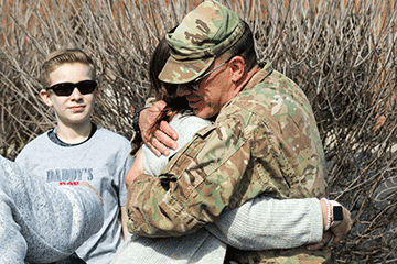 Soldiers hugs fanily member.