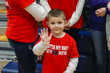 Boy waves to camera wearing shirt that read " OUTTA MY WAY I GET MY DADDY BACK TODAY"