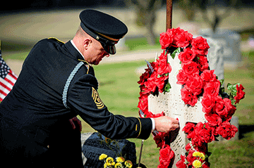 Soldier kneels at grave marker.