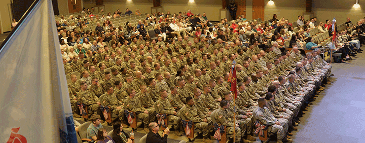 Soldiers sit in rows inside school.