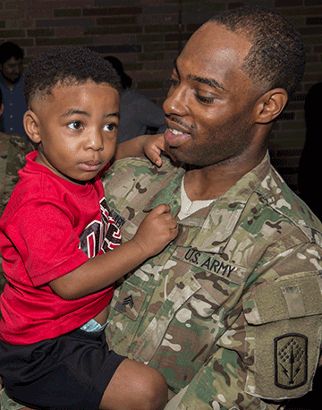 Soldier holds toddler son.