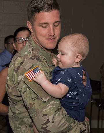 Soldiers embraces infant son.