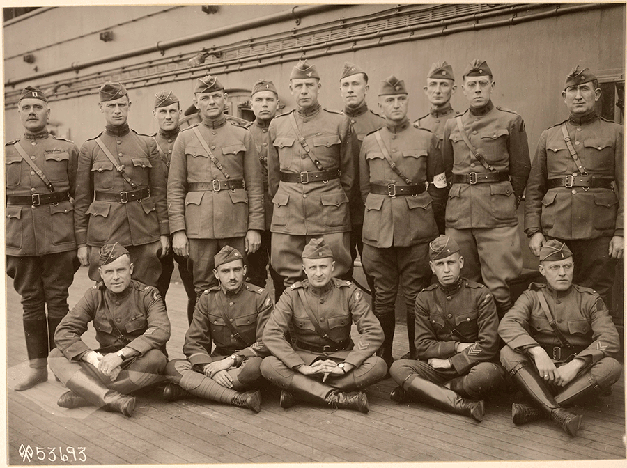 Sepia-tone photo of Soldiers standing in front of trains.