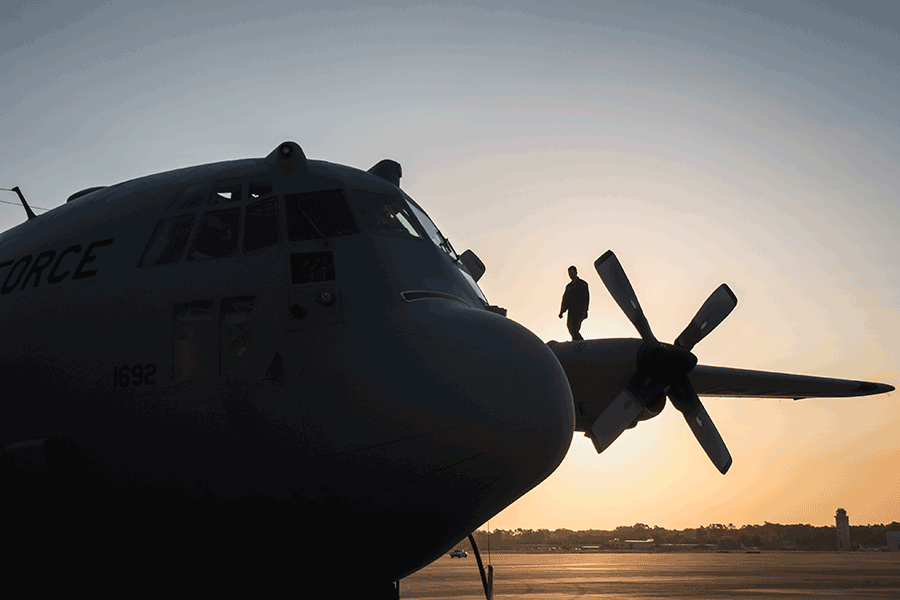 Loadmaster stands on top pf C-130H Hercules in the early morning sun.