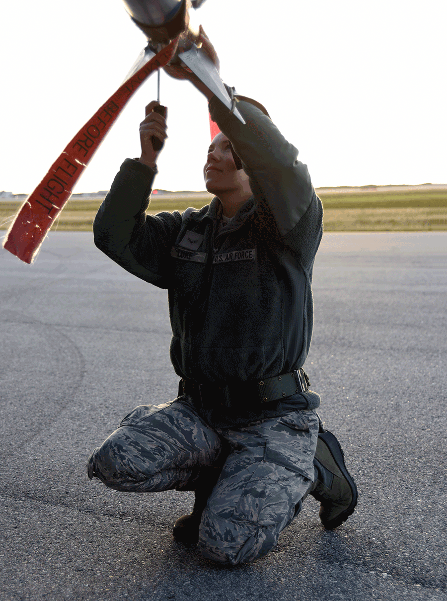 SFemal Airman kneels to workwork on missel. 
