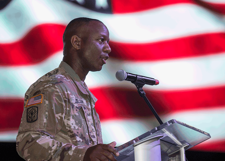 Soldier at podium with American flag behind.