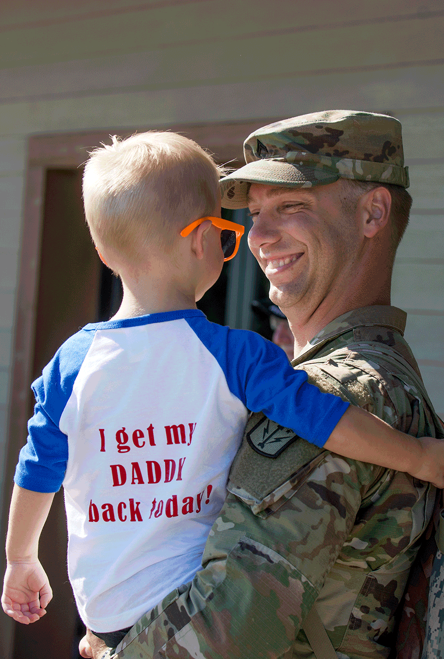 Soldier holds his son Robbie with t-shirt that reads: I get my DADDY back today.