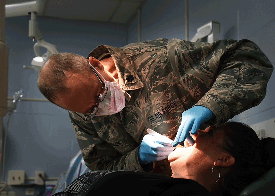 Airmen looks inside child's mouth.