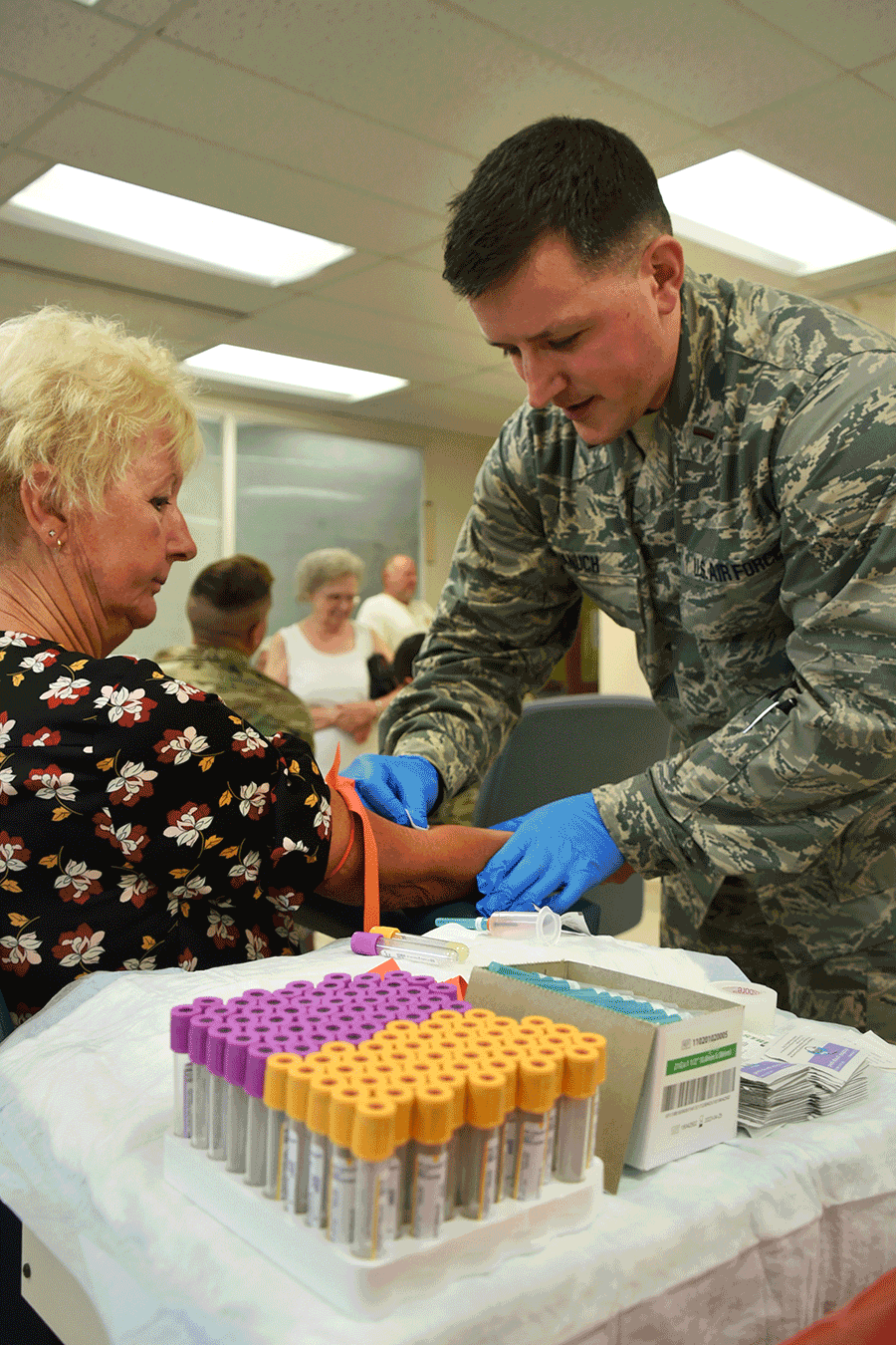 An Airman conducts a blood draw  on woman.