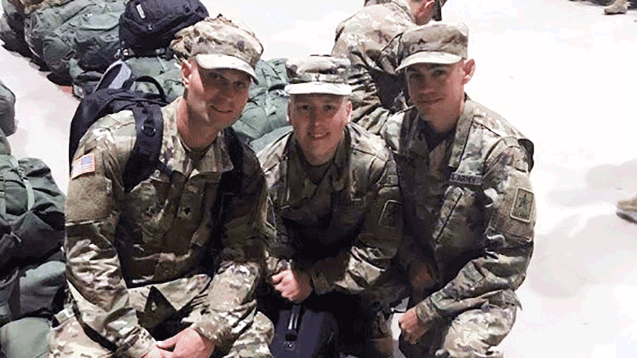 Three Soldiers in camo kneel together for photo