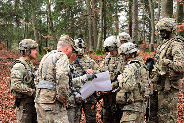 Soldiers gathered around a map in the woods